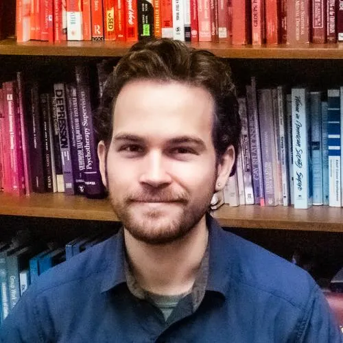 White male with short brown hair wearing a navy blue long sleeve shirt