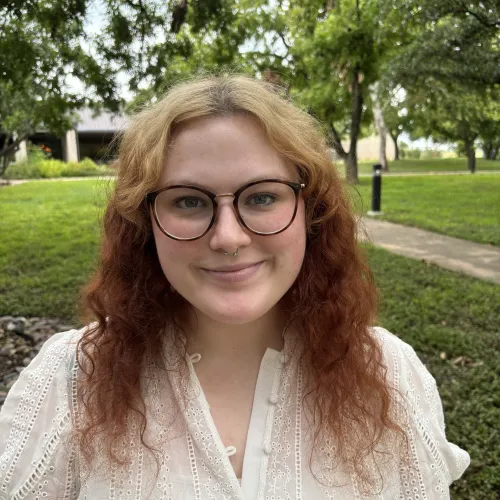 image of Adra Mersinger wearing glasses and a white top.