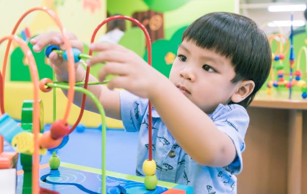 toddler with short black hair playing with toy