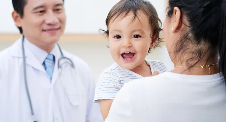 image of a doctor in front of a dark hair mom who is holding her baby with short dark hair
