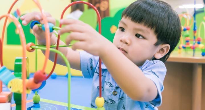 toddler with short black hair playing with toy